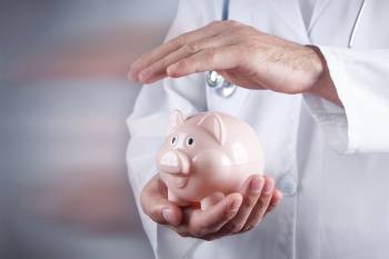 Foto: Arzt hält Hand über Sparschwein